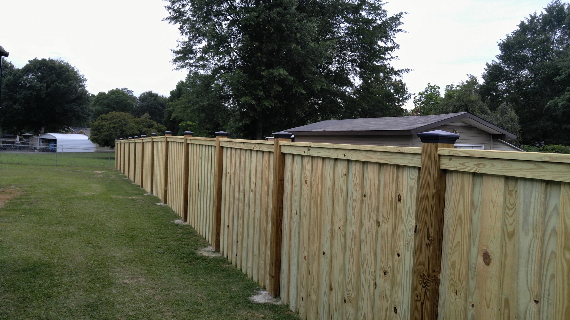 long wood fence with fence post caps installed